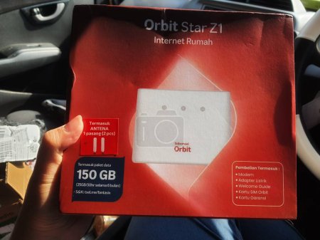 Téléchargez les photos : Jakarta, Indonésie en mars 2023. Une main tient une boîte et une carte d'un modem avec le produit Orbit Star Z1 Internet Rumah marque émise par Telkomsel, Telkom Indonésie. Inclure Antena (2 pièces) - en image libre de droit