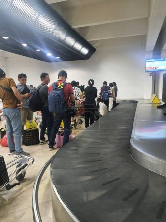 Téléchargez les photos : Cengkareng, Indonésie, le 9 juillet 2023. Plusieurs personnes attendent que leurs valises passent par le convoyeur au terminal 2F de l'aéroport de Soekarno Hatta - en image libre de droit