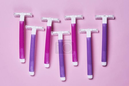 Photo for Three purple and white razors on a pink background with copy space in the top right handout is shown - Royalty Free Image