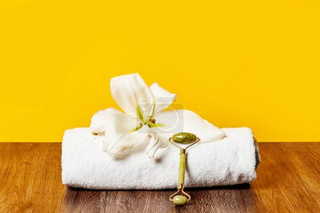 Téléchargez les photos : Une serviette avec une fleur sur une table en bois à côté d'un mur jaune et un plancher en bois brun - en image libre de droit