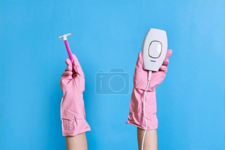 Téléchargez les photos : Certains mains tenant une brosse à dents électrique devant leurs doigts, sur un fond bleu avec espace de copie - en image libre de droit