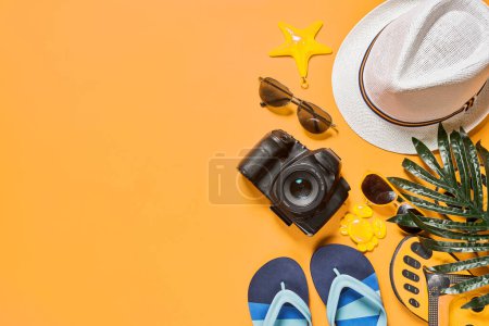 Téléchargez les photos : Un chapeau, des lunettes de soleil, des tongs et d'autres articles disposés sur un fond orange avec espace pour le texte - en image libre de droit