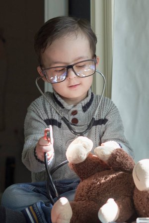Foto de Un niño pequeño jugando con un oso de peluche y stel delante de las gafas de los niños - Imagen libre de derechos