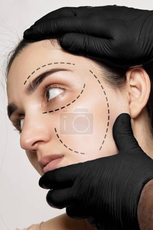 Photo for A womans face with lines drawn across the forehead and on her left hand is a pair of black gloves - Royalty Free Image