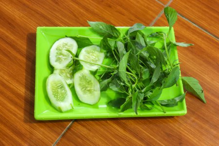 Téléchargez les photos : Légumes frais, il y a des feuilles de concombre et de basilic dans une assiette - en image libre de droit
