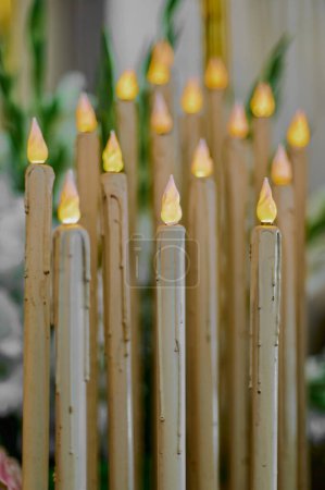 Photo for Vertical photo of a group of artificial plastic candles with bulbs simulating flames with the first being in selective focus. - Royalty Free Image
