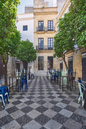 Photo for An inviting outdoor cafe with blue chairs on a cobblestone street, surrounded by historic architectur - Royalty Free Image