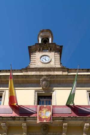 Blick auf das Rathaus von Jerez de la Frontera mit seinem Uhrturm und seinen Flaggen unter einem klaren blauen Himmel