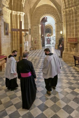 Photo for Jerez de la Frontera, Spain - February 03, 2024: Cleric in the cathedral of Jerez de la Frontera attentively accompanied by two altar boys who precede him. - Royalty Free Image