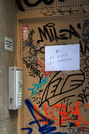 Photo for Barcelona, Spain - February 27, 2024: Door full of graffiti and a paper stuck with anti-drug text. Translation: The narcopiso is no longer there. on a portal in Barcelona. - Royalty Free Image