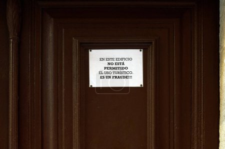 Image of a warning sign stuck on a brown door indicating the prohibition of tourist use of the building, calling it a fraud. Translation: Tourist use is not allowed in this building, it is a fraud