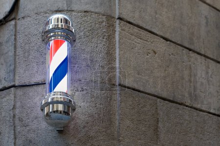 Photo for A classic barber pole with illuminated red, white and blue stripes, mounted on a stone wall on a street in Barcelona in Catalonia Spain - Royalty Free Image
