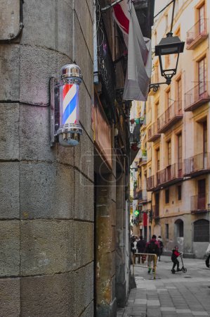 Photo for A classic barber pole with illuminated red, white and blue stripes, mounted on a stone wall on a street in Barcelona in Catalonia Spain - Royalty Free Image