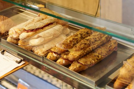 Appetizing artisanal sandwiches, ready for sale in a delicatessen display case.