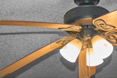 Photo for Closeup of a gold ceiling fan with lights on, adding a touch of elegance. - Royalty Free Image