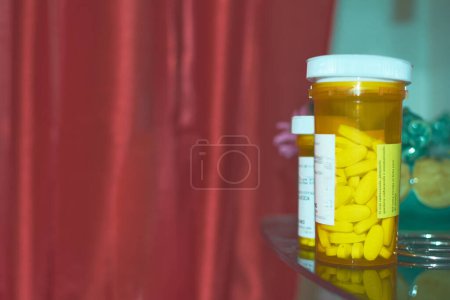 Téléchargez les photos : Flacon de médicaments jaune, étiquette blanche, fond rouge. - en image libre de droit