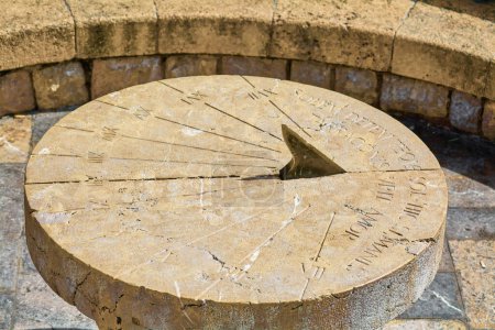 Este reloj de sol de piedra, situado en la histórica ciudad de Tarragona, muestra grabados numéricos y líneas horarias, reflejando la antigua medida del tiempo.