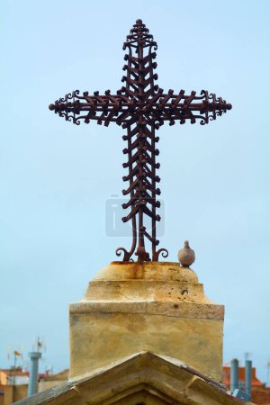 Foto de Dove se posó junto a una adornada cruz de metal, situada sobre una iglesia cristiana, bajo un cielo despejado. Es una representación serena y reverente de la fe y la naturaleza como el espíritu santo - Imagen libre de derechos