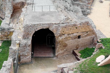 Blick auf den Eingang eines antiken römischen Amphitheaters in Tarragona, das die robuste Architektur und die umgebende natürliche Schönheit präsentiert. Ein Blick in die Vergangenheit durch historische Ruinen.