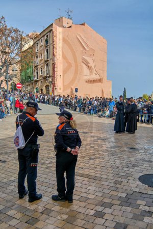 Téléchargez les photos : Tarragone, Espagne - 23 avril 2024 : Image de deux agents de la protection civile en uniforme, face à l'arrière, supervisant un événement public dans une rue urbaine, assurant la sécurité et l'ordre - en image libre de droit