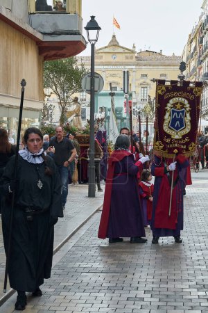 Photo for Tarragona, Spain - April 23, 2024: Cultural event of Holy Week with religious figures and devotees in ceremonial attire moving through an urban area. - Royalty Free Image