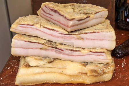 Detailed image of three slices of cured bacon stacked, showing the alternating layers of meat and fat. Perfect for representing high-quality ingredients in gourmet cuisine