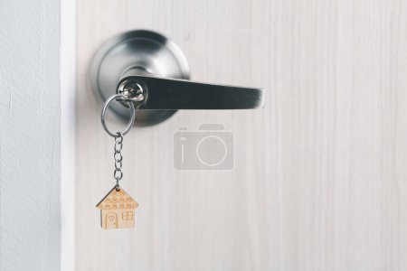 Photo for Close up key on the door with morning light, personal loan concept. House model and key in house door. Real estate agent offer house, property insurance and security, affordable housing concepts. - Royalty Free Image