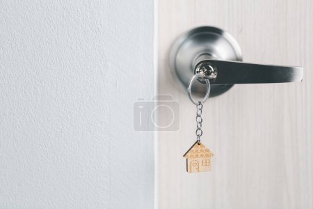 Photo for Close up key on the door with morning light, personal loan concept. House model and key in house door. Real estate agent offer house, property insurance and security, affordable housing concepts. - Royalty Free Image