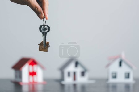 Schlüssel zu Ihrem eigenen Haus in der Handfläche des Mädchens und ein Holz für die Vermietung von Immobilien. Hausmodell und Schlüssel in der Haustür. Immobilienmakler bieten Haus- und Grundversicherung an.