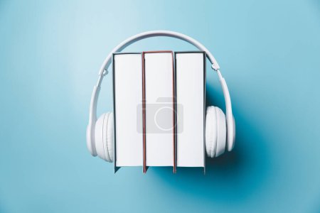 Photo for White headphones with stack of books on blue background. Audio books or modern education concept. Copy space for text. Distance education, e-learning concept. Top view with space for your text. - Royalty Free Image