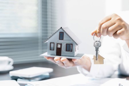 Gerente de ventas o agente de bienes raíces se prepara para entregar las llaves y la casa junto con el seguro al cliente, Atención a los servicios inmobiliarios y concepto de seguro.