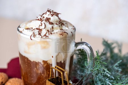 Photo for Close-up of white whipped cream foam on coffee latte in glass, grated chocolate chips. Juniper branch in the background for Christmas mood. Copy space. High quality photo - Royalty Free Image