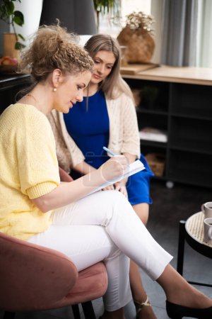 Zwei Frauen in Coaching oder Psychotherapie, eine macht Notizen, beschwört eine konzentrierte Lernatmosphäre und Geschäftswachstum herauf. Hochwertiges Foto