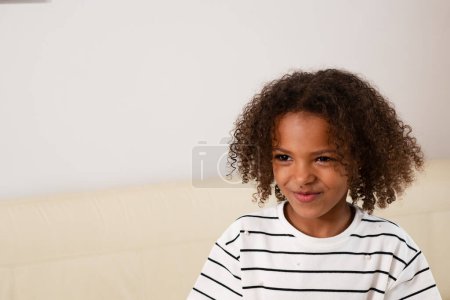 Ein fröhliches Kind gemischter Rassen im gestreiften Hemd, das Glück und Vielfalt verkörpert, ideal für Themen wie Jugend, Positivität und multikulturelles Feiern. Hochwertiges Foto