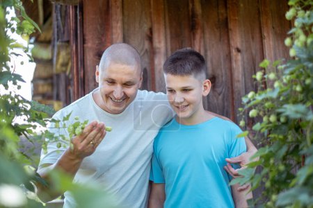 A man and a boy, father and son, share a moment of joy while examining plants in a garden against a wooden backdrop, family bonding time and health insurance on trips. High quality photo