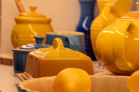 Vibrant yellow and blue ceramic kitchenware, including teapots and lemon colored dishes, evoking a warm, homey atmosphere, perfect for culinary or domestic settings. High quality photo