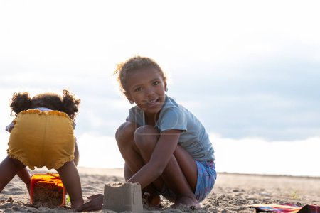 two sisters, Children engage in sandy construction on a beach, their joy and teamwork evident in the beachside play, National Siblings day and cooperation. High quality photo