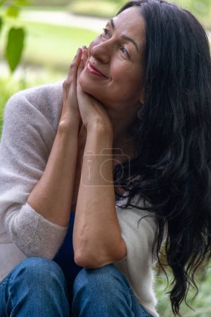 Captured in a moment of reflection, this image of a smiling woman could represent themes like mental well-being, the joy of solitude, and the beauty of aging with grace. High quality photo