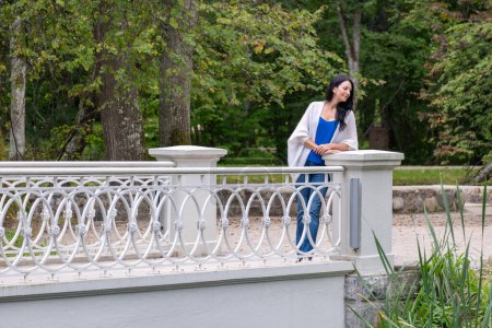 Une femme contemplative se tient près d'un pont au-dessus de l'eau calme dans un cadre luxuriant, évoquant la réflexion de la quarantaine et la connexion avec la nature. Photo de haute qualité