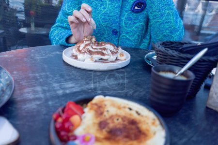 Eine Person in Blau genießt Tiramisu in einem Café im Freien und fängt die Essenz gemächlichen Essens ein. Hochwertiges Foto