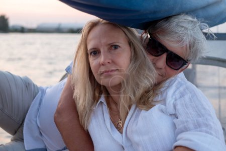 Mature couple in a serene embrace, a moment of connection on the water, with the calmness of dusk reflected in their content expressions. High quality photo