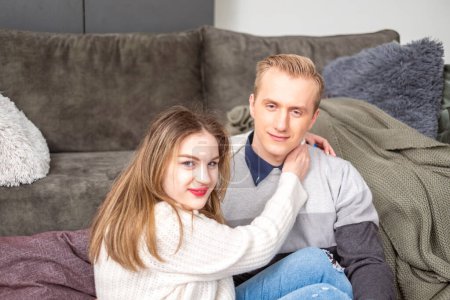 Close up of a loving embrace, with a woman in a white sweater and a man in a grey striped top, conveying warmth and happiness in a home environment. High quality photo