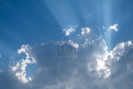 Sunbeams radiating through silver lined clouds in a vivid blue sky. Ideal for concepts of hope and inspiration. High quality photo