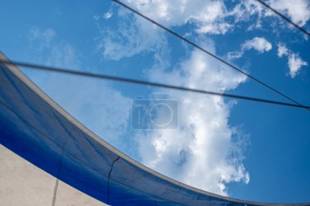 Téléchargez les photos : Voiles bleues et blanches contre un ciel nuageux, encadrées de cordes tendues. Capte l'essence de la voile aventure. Photo de haute qualité - en image libre de droit