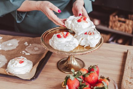 Téléchargez les photos : Mains d'un cuisinier garnissant desserts meringues, élégante toile de fond de cuisine. Pour les blogs gastronomiques. Photo de haute qualité - en image libre de droit