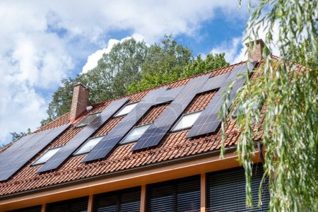 Photovoltaic panels atop a house illustrate the growing adoption of solar energy in urban settings, reflecting a move towards eco sustainability and smart homes. High quality photo