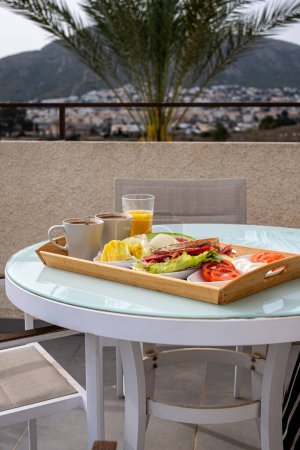 Un desayuno en la azotea con vistas panorámicas a la montaña, con una comida saludable y zumo fresco, ideal para viajes y temas de estilo de vida. Foto de alta calidad