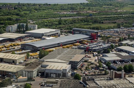 Foto de Slough, UK - April 26, 2022:  Aerial view of an industrial estate in Colnbrook, Slough which includes the Southern Hub of DHL Express. The warehouses are next to Heathrow Airport and the King George VI Reservoir is in the distance. - Imagen libre de derechos