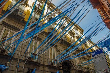 Foto de Vista hacia arriba a través de banderines azules y blancos, banderas y serpentinas en el centro histórico de la ciudad de Nápoles mientras los residentes celebran el éxito de la S.S.C. Club de fútbol Napoli. - Imagen libre de derechos