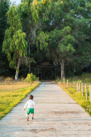 Téléchargez les photos : Route qui pénètre dans la forêt et courir enfant - en image libre de droit